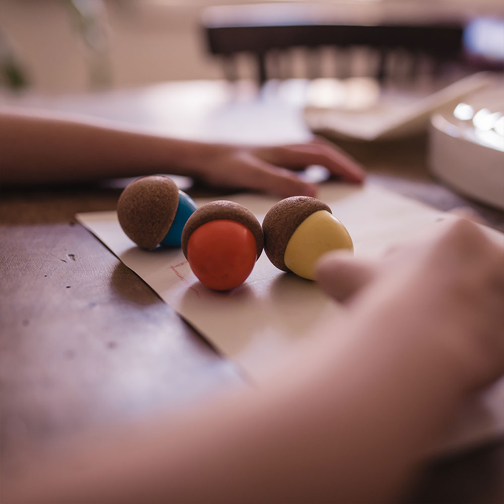Três esponjas de maquilhagem coloridas em cima de papel numa mesa de madeira