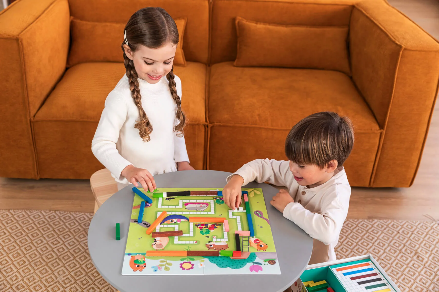 Crianças a jogar jogo de tabuleiro com peças de madeira coloridas num ambiente interior.