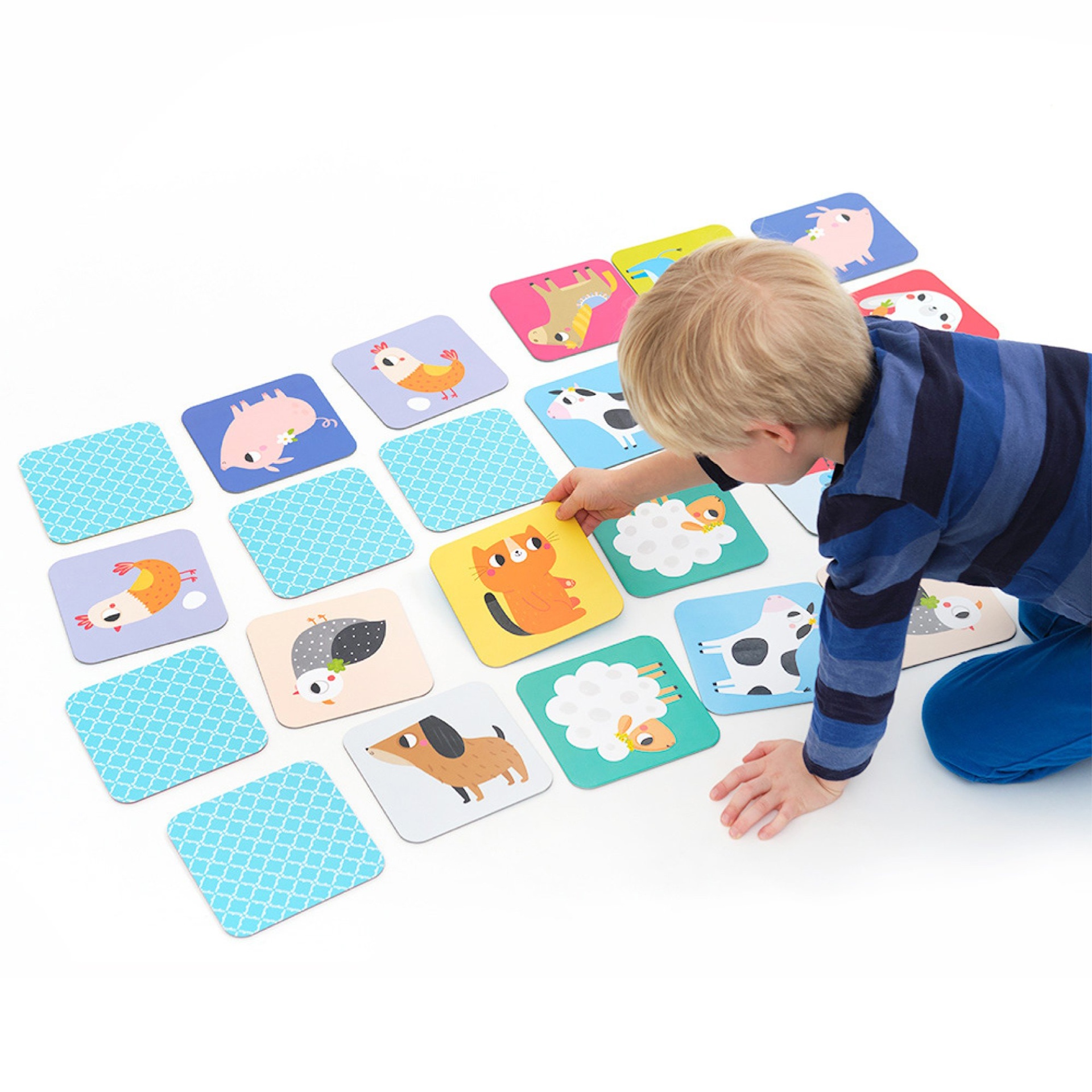 Jogo de memória com cartas de animais e menino loiro a jogar.