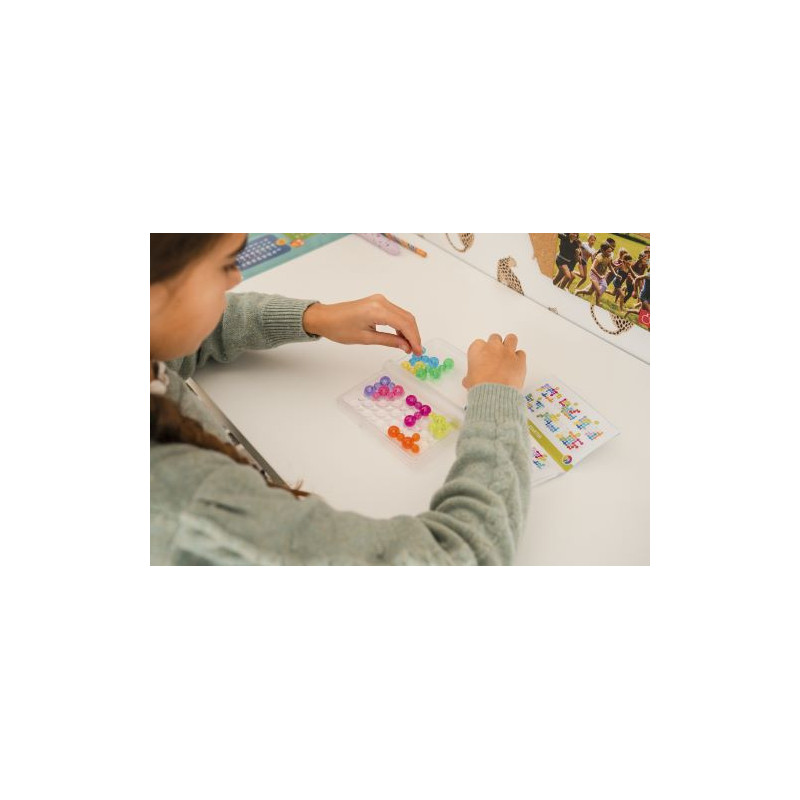 Criança a montar peças de plástico coloridas translúcidas numa mesa branca