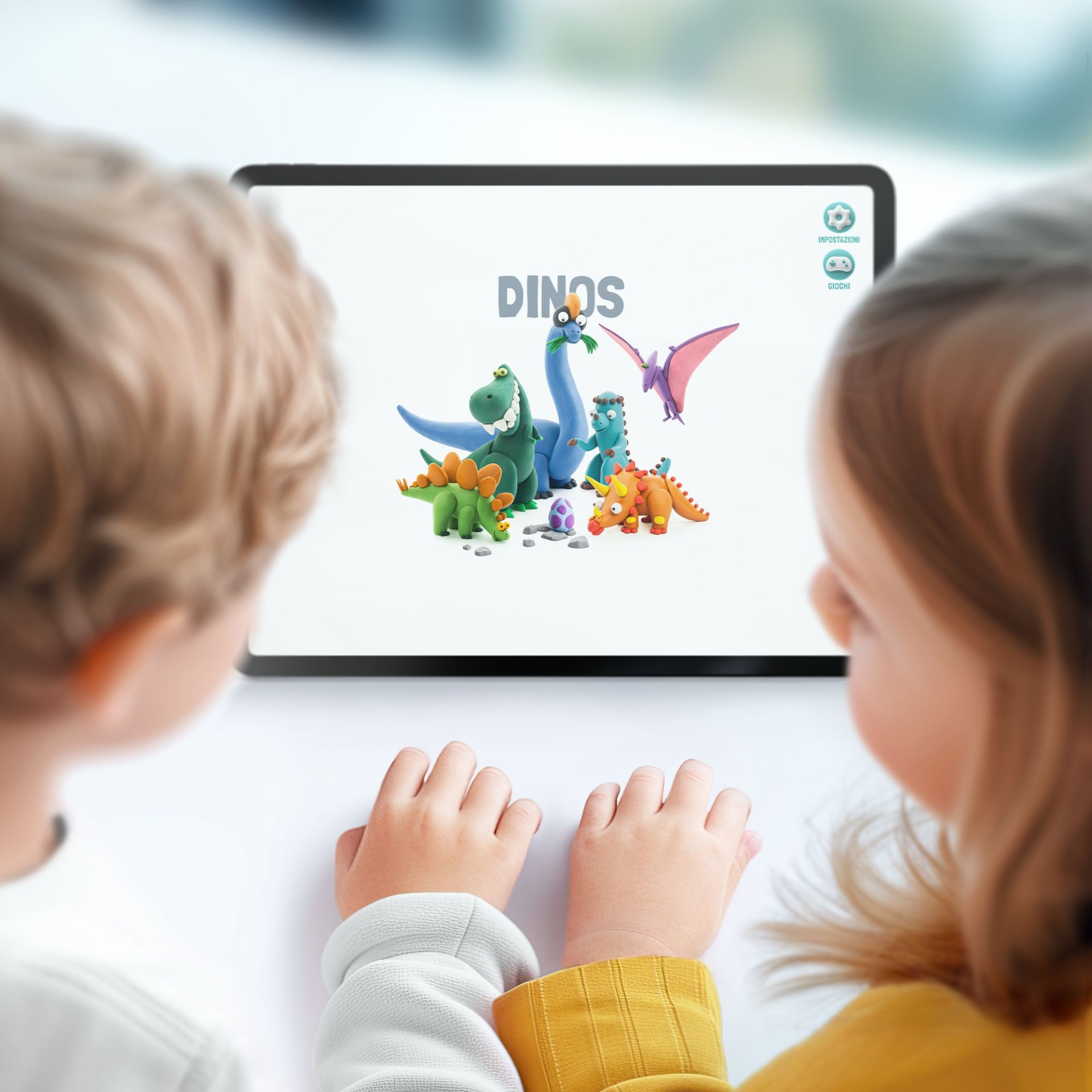 Tablet com ecrã branco exibindo dinossauros coloridos de brinquedo e texto DINOS, visto pela perspetiva de duas crianças.