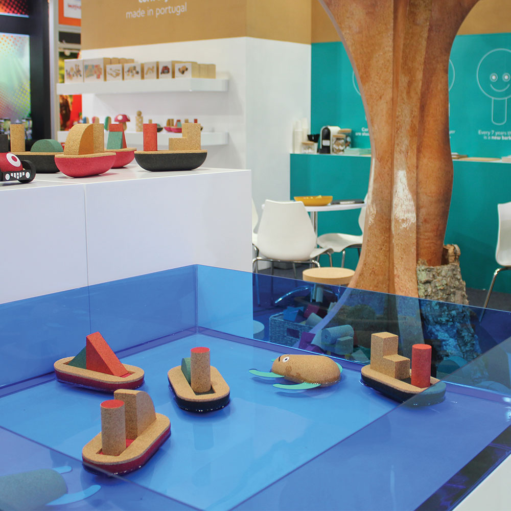 Modelos decorativos de barcos em madeira e cortiça sobre superfície azul com ambiente de sala ao fundo