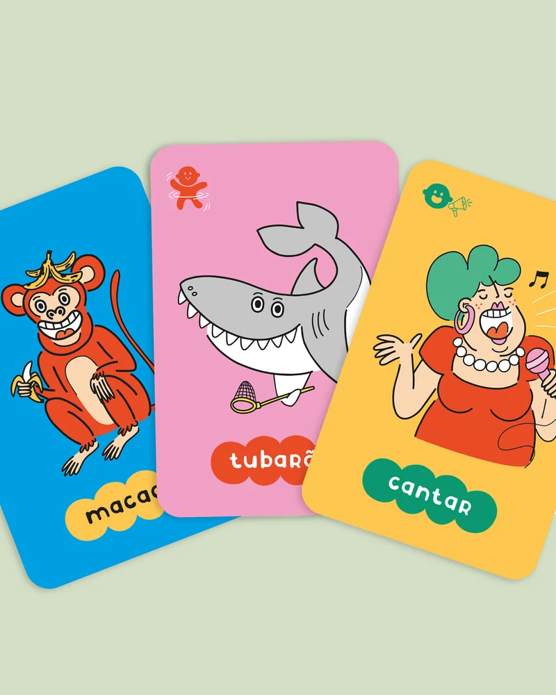 Três cartas coloridas com desenhos de um macaco, um tubarão e uma mulher a cantar.