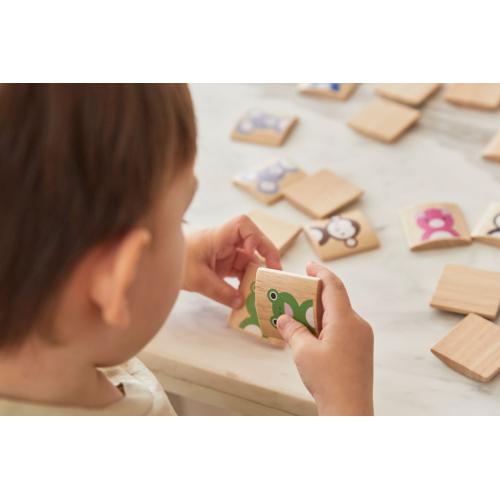 Peças de jogo de memória de madeira com imagens de animais coloridos sendo manuseadas por uma criança