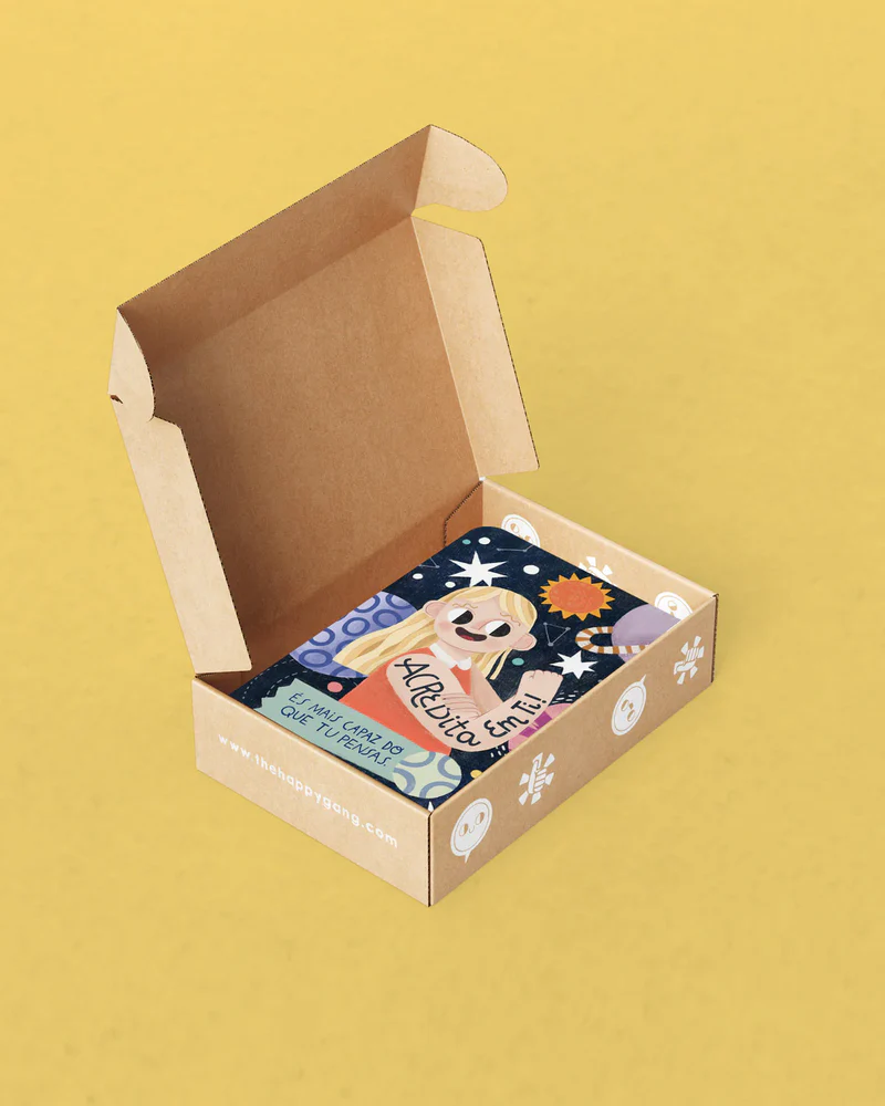 Caixa de cartão aberta com caderno ilustrado colorido dentro sobre fundo amarelo