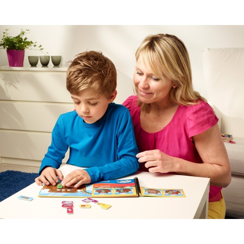 Criança e mulher a brincar com livro de atividades numa mesa interior branca