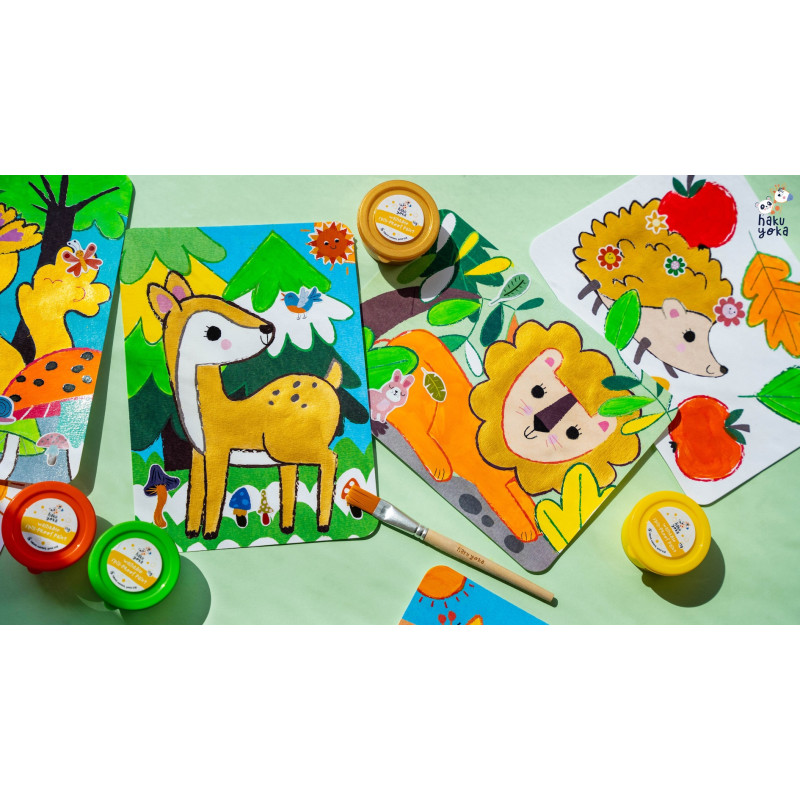 Placas infantis coloridas com desenhos de animais e tintas e pincel sobre mesa clara