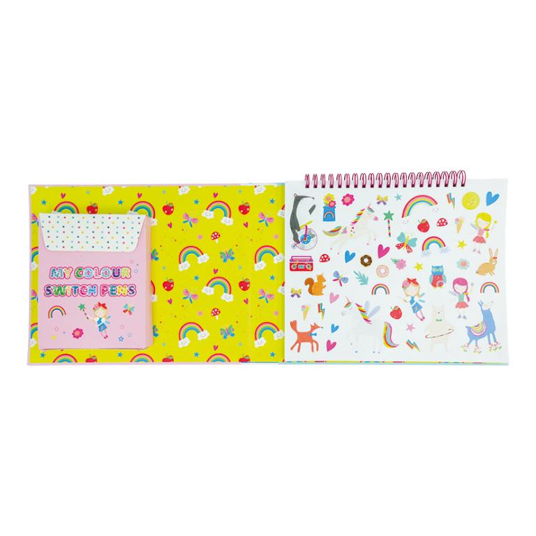 Conjunto infantil com caixa rosa 'MY COLOUR SWITCH PENS' e caderno aberto com padrão amarelo, arcos-íris e autocolantes coloridos.