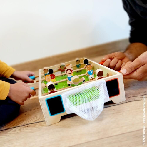 Jogo de futebol de mesa em madeira com jogadores coloridos e redes brancas nas balizas