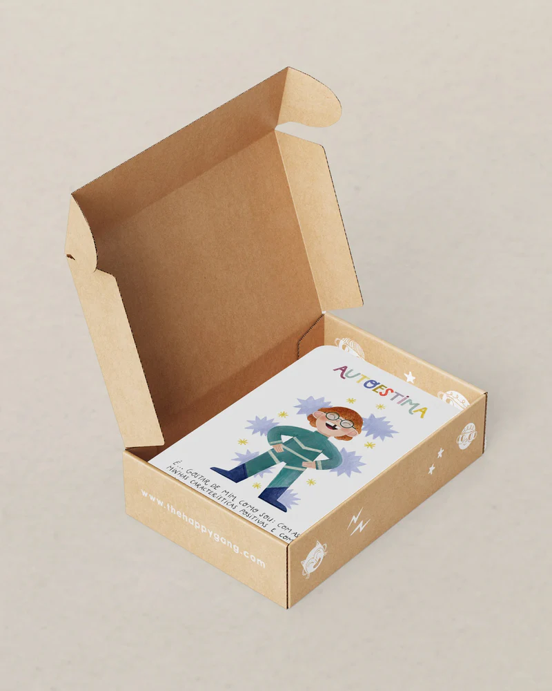Caixa de cartão aberta com cartas ilustradas e palavra AUTOESTIMA