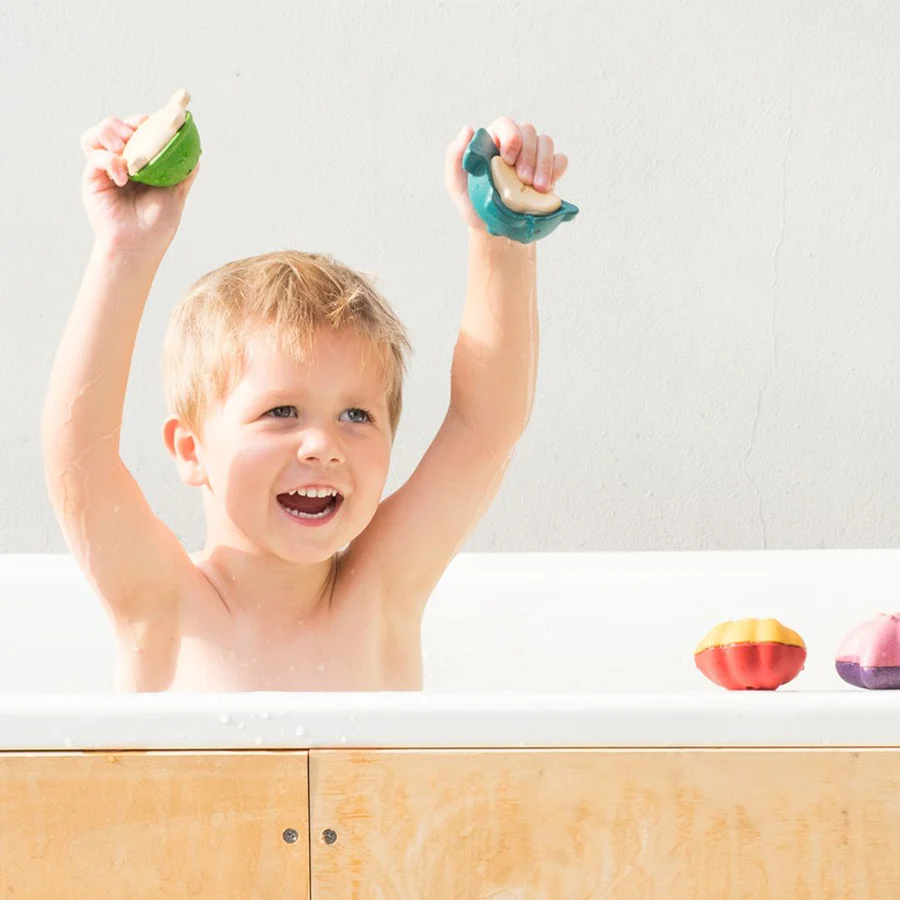Criança na banheira a brincar com brinquedos coloridos em forma de media casca de fruta