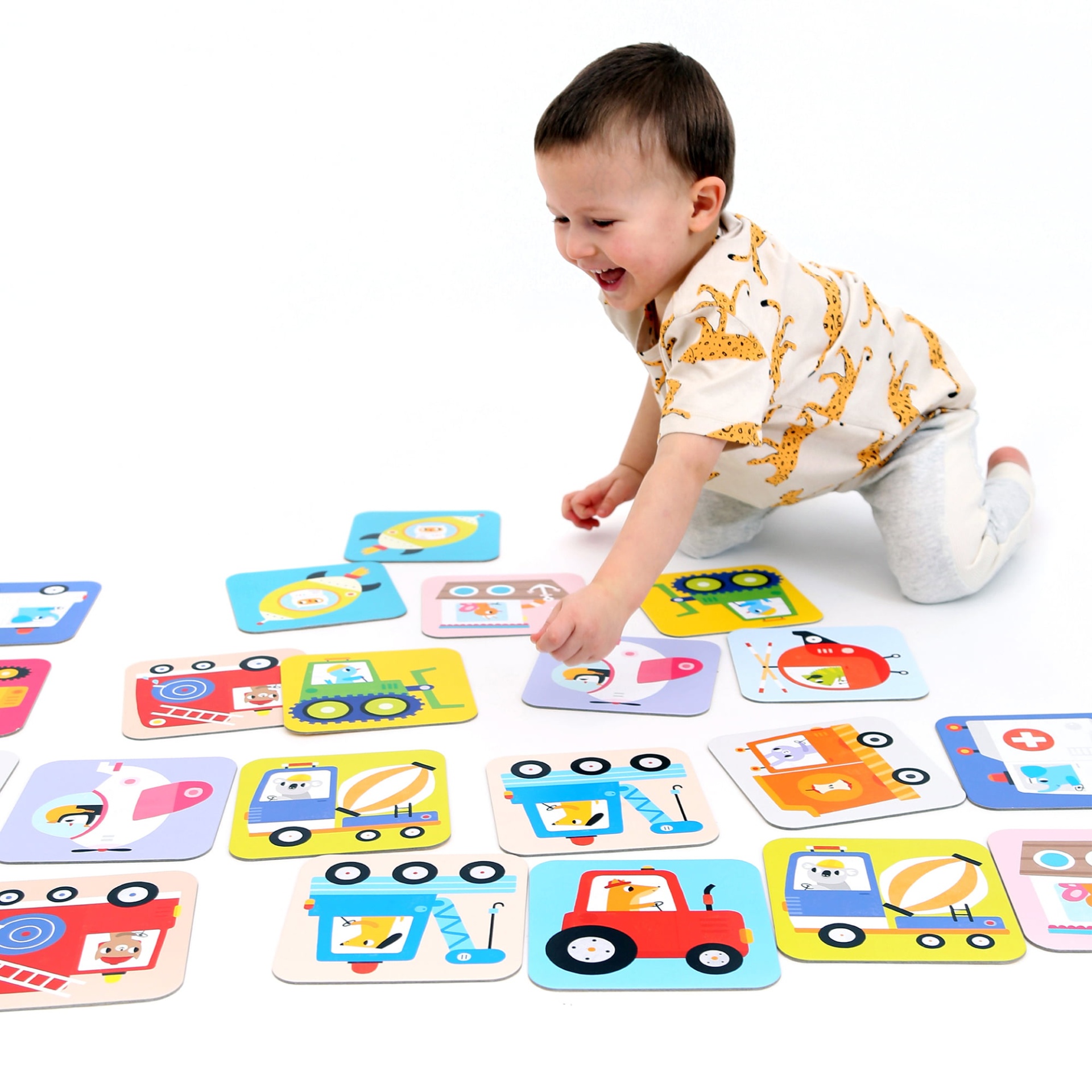 Criança a brincar com cartas ilustradas de veículos em fundo branco