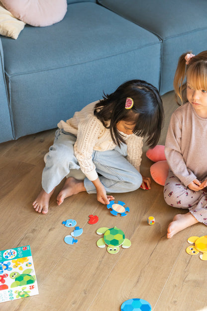Crianças a jogar com puzzle de peças coloridas no chão junto a sofá azul