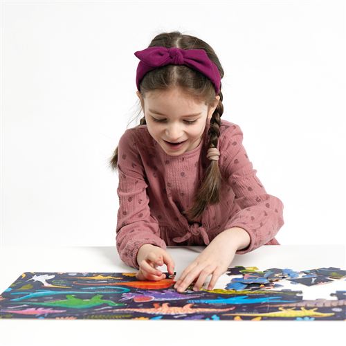 Criança com vestido rosa e tiara roxa a montar puzzle de dinossauros