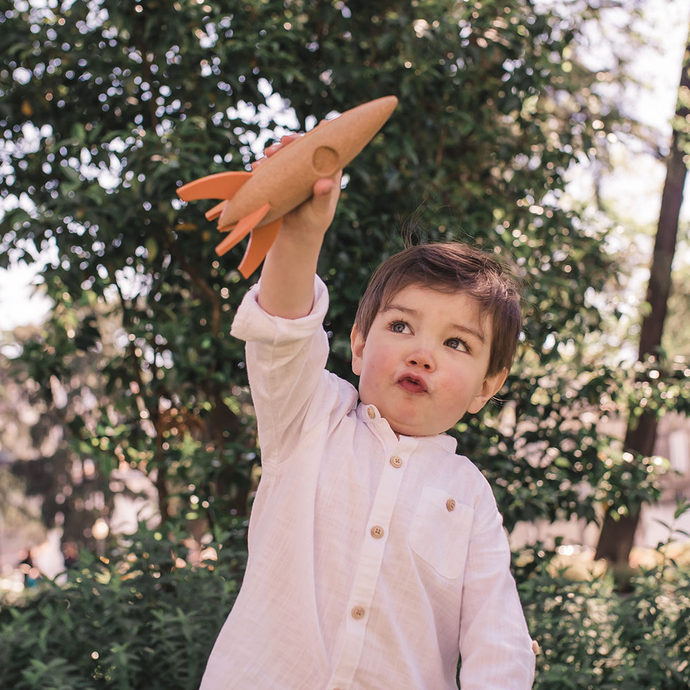 Menino com brinquedo foguete cor laranja ao ar livre