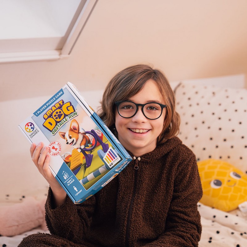 criança com jersey castanho e óculos a segurar jogo de puzzle Smart Dog Obstacle Run