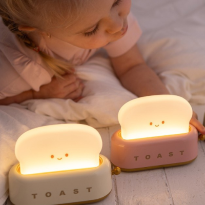 Duas lâmpadas em forma de torrada com carinha sorridente em suportes branco e rosa com a palavra TOAST