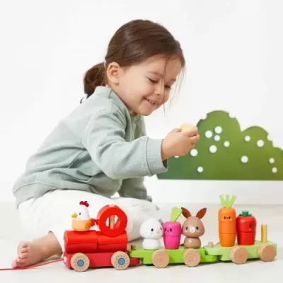 Menina a brincar com comboio de madeira colorido com figuras de animais e vegetais
