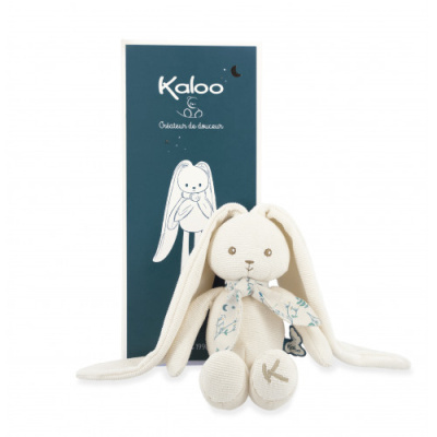 Urso de peluche branco com orelhas compridas Kaloo junto a caixa azul com desenho e texto