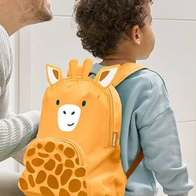 Mochila infantil laranja com estampa de girafa usada por criança