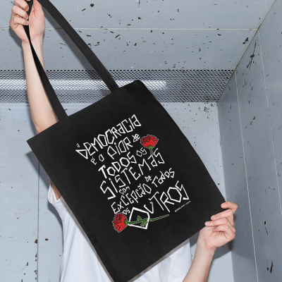 Mala de pano preta com texto branco e rosas vermelhas segurada por pessoa com t-shirt branca