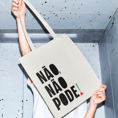 Mala de tecido bege com texto preto NÃO, NÃO PODE em fundo metálico cinzento.