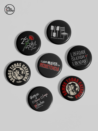 Bottons redondos pretos com frases e desenhos em várias cores.