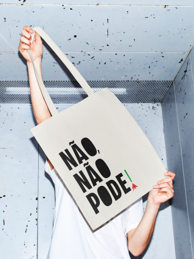 Mala de tecido bege com texto preto NÃO, NÃO PODE em fundo metálico cinzento.