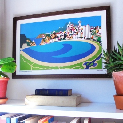 Quadro ilustrativo colorido de paisagem costeira emoldurado numa parede acima de prateleira com livros e plantas