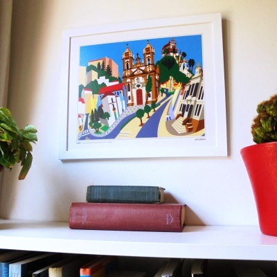 Quadro ilustrativo colorido numa parede com livros e plantas numa prateleira branca.