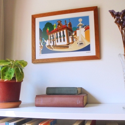 Livro antigo, planta em vaso castanho, moldura de madeira com ilustração de casa colorida