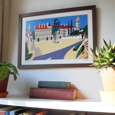 Pintura emoldurada de uma praça com estátua equestre, livros e plantas em ambiente interior
