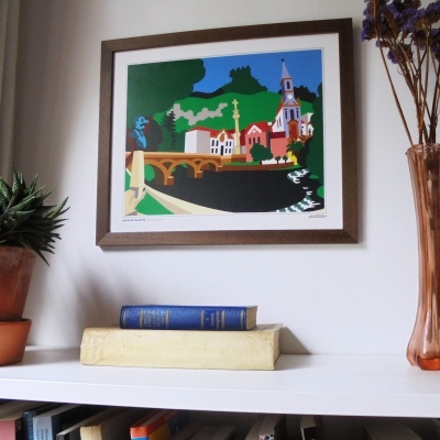 Quadro de paisagem urbana colorida em moldura de madeira, prateleira com livros, planta e vaso com flores secas