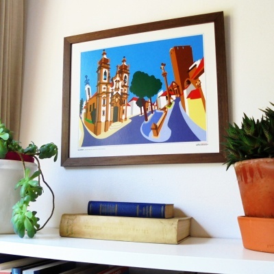 Quadro emoldurado colorido com ilustração de rua e edifícios, plantas em vasos e livros na estante
