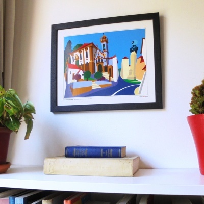 Quadro colorido em moldura preta na parede com livros e plantas em prateleira branca