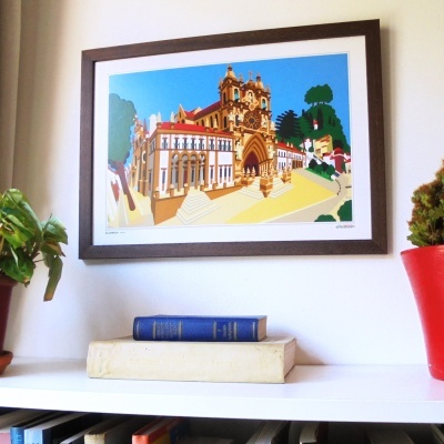 Quadro ilustrado colorido em moldura castanha sobre prateleira branca com livros e plantas