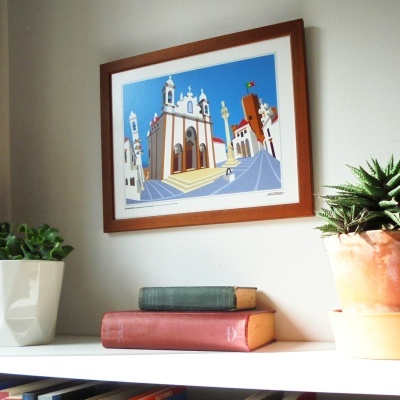 quadro com pintura arquitetónica em moldura de madeira pendurado numa parede entre plantas em vasos em estante branca