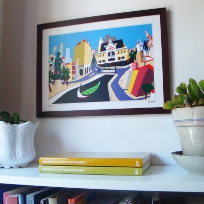 Estante com livros de arte portuguesa, quadro colorido de cidades e plantas em vasos