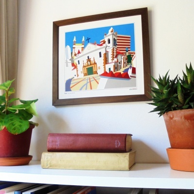 Estante branca com vasos, livros e moldura com ilustração colorida de edifícios