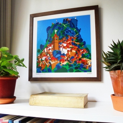 Quadro colorido emoldurado de paisagem com plantas e livro numa prateleira