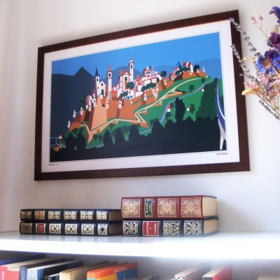 Quadro em moldura escura com ilustração de vila colorida na parede