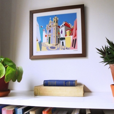 Quadro colorido emoldurado, mesa branca com livros empilhados e plantas em vasos