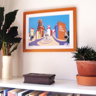 quadro colorido emoldurado numa parede branca com plantas e uma caixa decorativa sobre estante branca