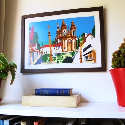 Quadro colorido com igreja barroca, livros empilhados e plantas em vaso na prateleira branca