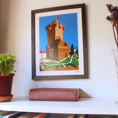 Quadro ilustrativo de castelo com moldura castanha em parede branca
