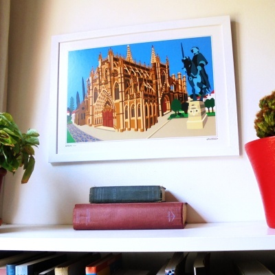 Ilustração emoldurada de edifício gótico e estátua pendurada na parede acima de plantas e livros