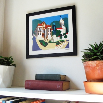 Estante branca com livros, plantas em vasos e quadro preto com arte gráfica colorida na parede