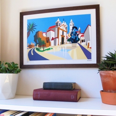 Quadro emoldurado com ilustração colorida de edifícios e paisagem, acima de prateleira com livros e vasos com plantas.