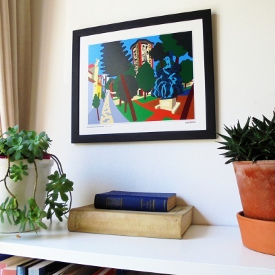 Quadro colorido na parede com plantas e livros em superficie branca