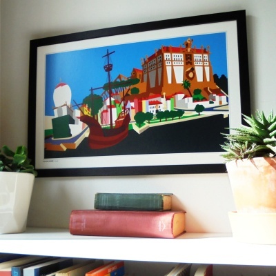 Quadro colorido pendurado na parede com plantas e livros em estante branca